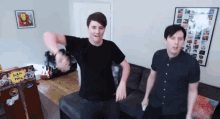 two men are dancing in a living room in front of a sign that says dan and phil