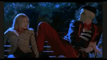 a man and a woman are sitting on a bench . the man is wearing a mask .