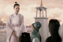 a woman in a pink robe stands in front of a group of children