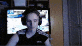 a young man wearing headphones and an adidas shirt