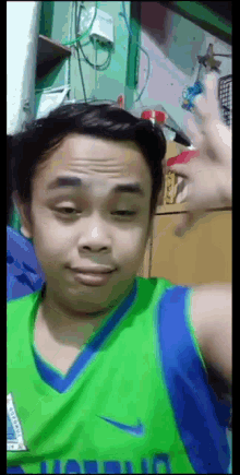a young man wearing a green nike jersey is making a face