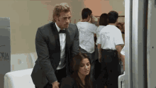 a man in a tuxedo stands next to a woman wearing a victoria t-shirt
