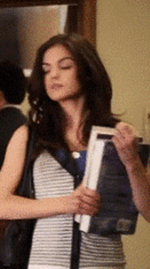 a woman in a striped shirt is holding a book in her hand
