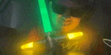 a person wearing sunglasses is holding a green light saber in their hand .