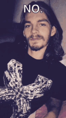 a man with long hair and a beard is wearing a black shirt with a cross on it and says no
