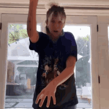 a woman in a blue shirt is dancing in front of a large window