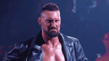 a shirtless wrestler holds his jacket over his head