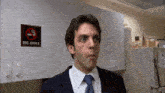 a man in a suit and tie stands in front of a sign that says no smoking