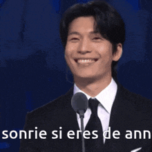 a man in a suit and tie is smiling with the words sonrie si eres de ann behind him