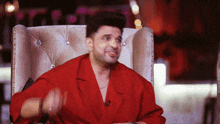 a man in a red shirt is sitting in a chair and smiling