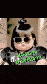 a little girl wearing sunglasses and a black dress with a bun on her head .
