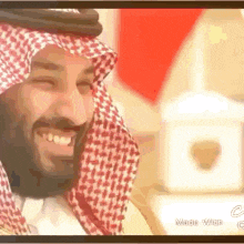a man with a beard wearing a red and white checkered scarf is smiling .