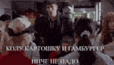 a man in a black jacket stands in front of a crowd of people and says " koly kartosku i hamburger " in russian