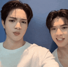 two young men are standing next to each other and one of them is wearing a white shirt