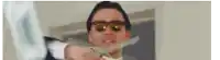 a man wearing sunglasses and a suit is throwing money in the air .