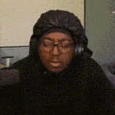 a man wearing glasses and headphones is sitting in front of a laptop .