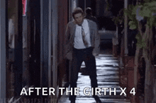 a man in a suit and tie is walking down a sidewalk at night .