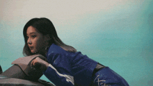 a woman in a blue leather jacket is sitting on a motorcycle .
