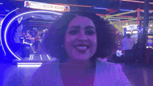 a woman giving a thumbs up in front of a sign that says ' arcade ' on it