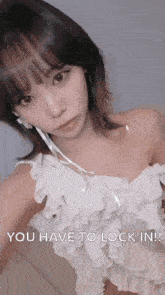 a woman in a white dress is taking a selfie with the words `` you have to lock in '' written below her .