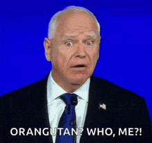 a man in a suit and tie is speaking into a microphone and says orangutan who me