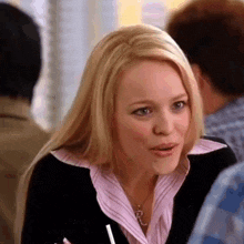 a woman is sitting at a table with a straw in her hand and making a funny face .