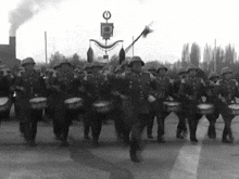 a black and white photo of soldiers marching in a parade with a flag with the letter o on it