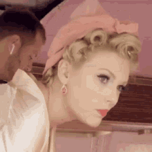 a woman is getting her hair done by a man while wearing a pink headband .