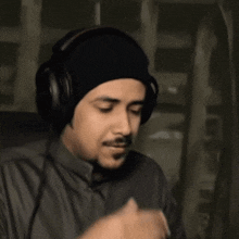 a man wearing a black beanie and headphones is clapping his hands