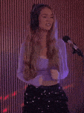 a woman wearing headphones is singing into a microphone in a recording studio .