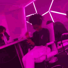a group of people are sitting in front of a wall with purple lights on it .