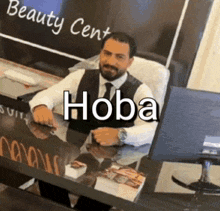 a man is sitting at a desk in front of a sign that says beauty center