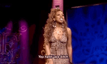 a woman in a dress is standing on a stage and talking to someone .