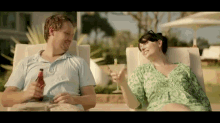 a man sitting next to a woman holding a bottle of coke