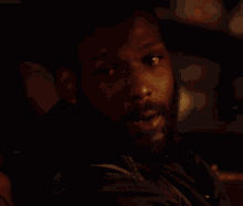 a close up of a man 's face with a beard in the dark