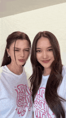 two women are posing for a picture with one wearing a t-shirt that says ' meow ' on it