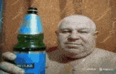 a shirtless bald man is holding a bottle with a blue label that says ' vhttab ' on it