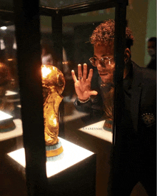 a man looking at a trophy in a glass case with the word cyaneynhu on the bottom