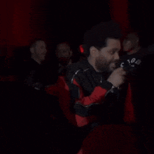 a man in a black jacket is laughing while standing in a crowd .
