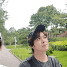 a man wearing a baseball cap and a necklace looks up at something
