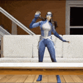 a woman in a blue superhero costume is standing in front of a white couch .
