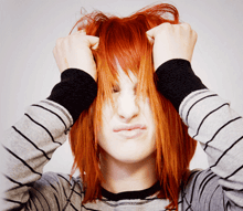 a woman with red hair holds her hair in her hands
