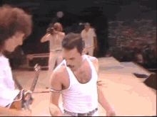 a man in a white tank top with a mustache is dancing on a stage .