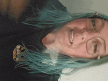 a woman with blue hair is wearing glasses and a black shirt that says ' ho ' on it