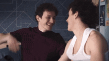 a man in a red shirt and a man in a white tank top are hugging each other