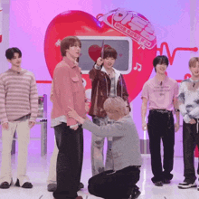 a group of young men are standing in front of a large red heart that says ' oiss ' on it