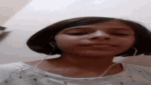 a woman wearing headphones and a white shirt looks down at the camera