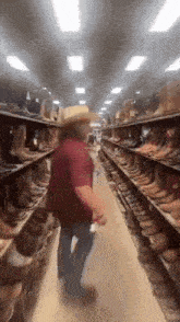 a man in a cowboy hat is walking down a aisle of cowboy boots .