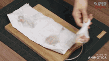 a person is holding a piece of paper towel on a wooden cutting board that says super recipes made in animotica