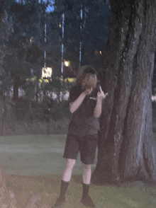 a person standing in front of a tree with their hand in the middle